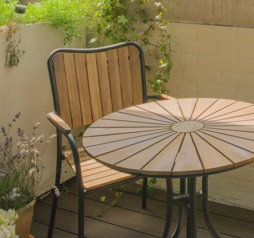 Une table de patio en bois avec une chaise assortie entourée de plantes.