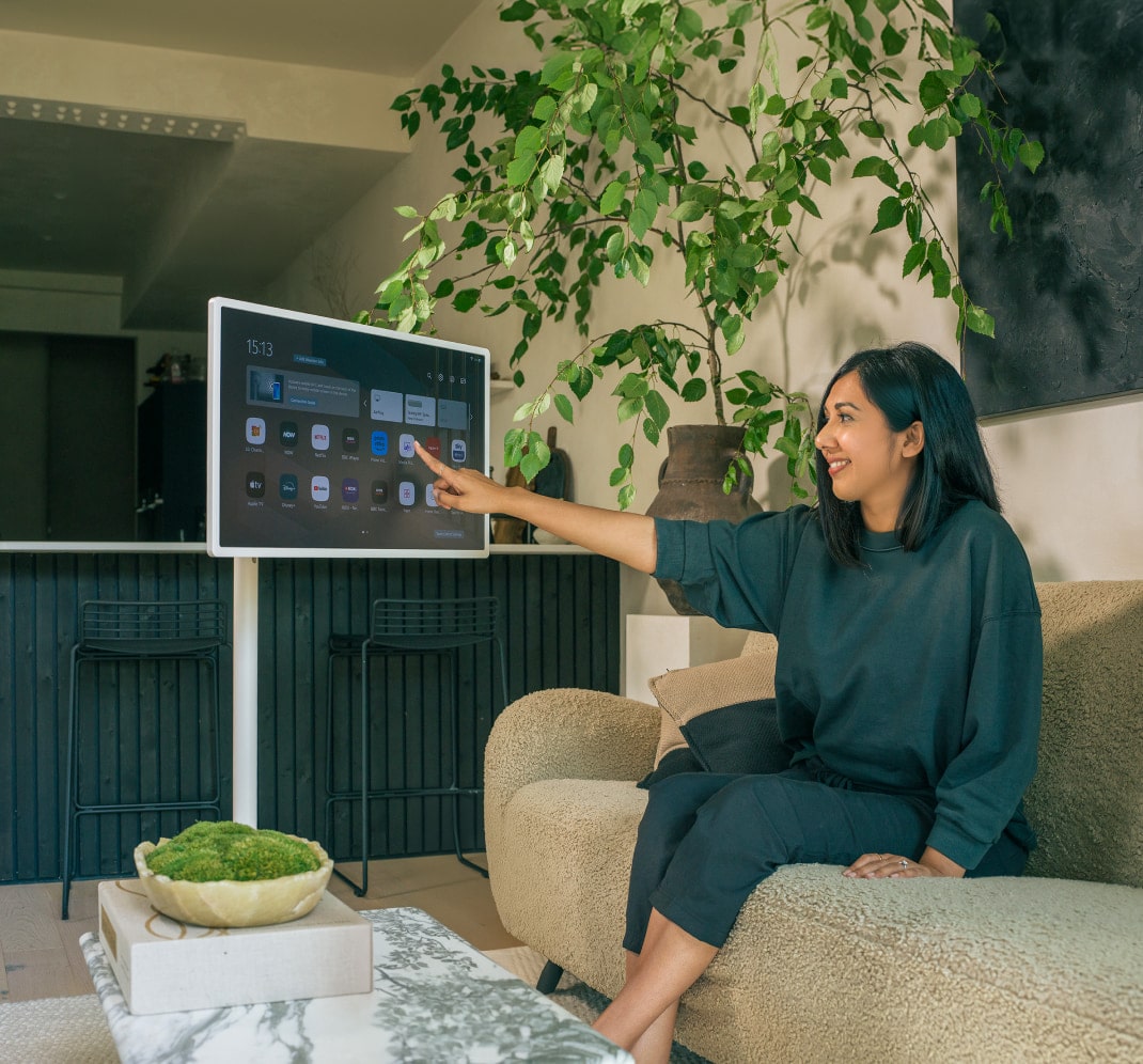 Lisa Mistry est assise sur son canapé, souriant en touchant l'écran du LG StandbyME.