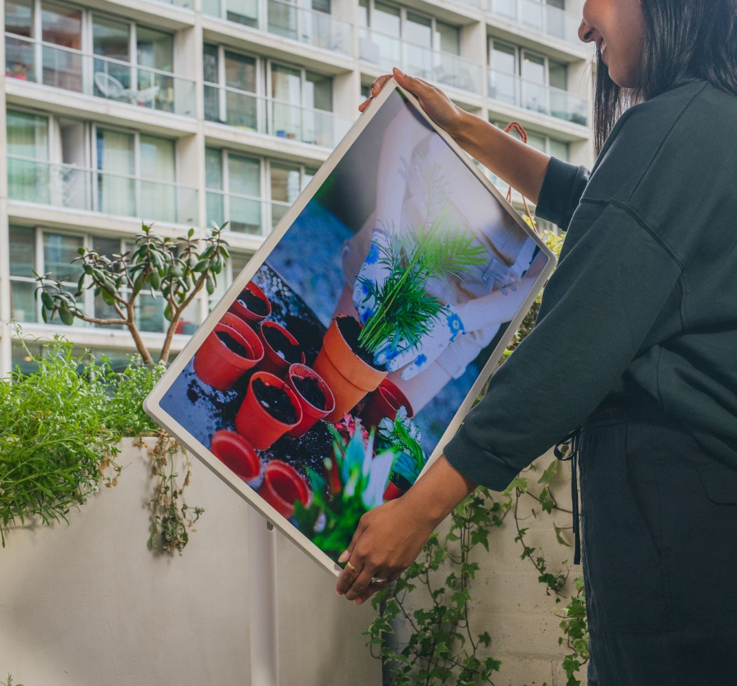 Lisa Mistry ajuste le LG StandbyME, qui diffuse une vidéo sur le rempotage des plantes, alors qu'elle est sur son balcon.