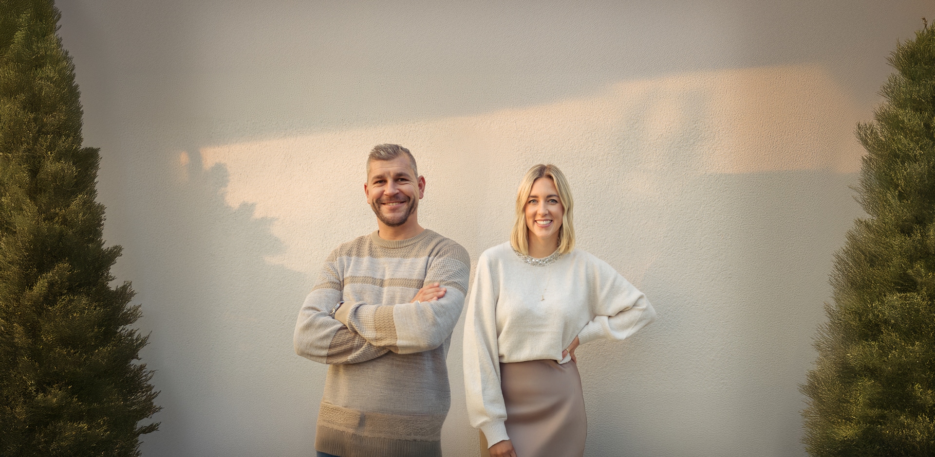 Un couple souriant entre deux sapins de Noël.