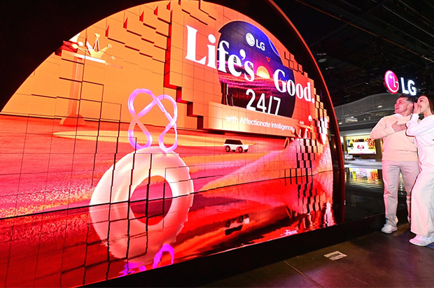 Visitors viewing LG curved LED display showcasing 'Life's Good 24/7' slogan at tech exhibition