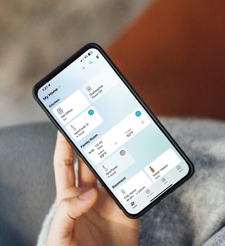 A person holds a smartphone with the LG ThinQ app open, managing smart home devices while drinking coffee.