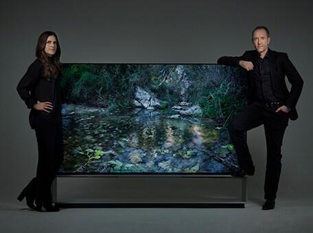 Artist duo Alexandrov Klum leaning on a LG SIGNATURE 88" TV