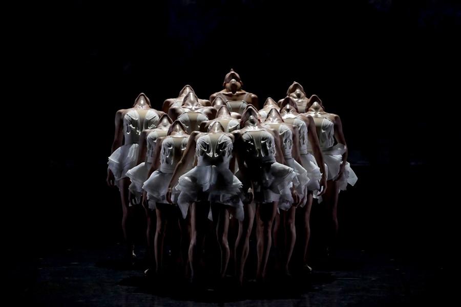 A photo of female dancers on stage with their heads tilted backward.