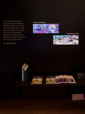 Illustrations from the OLED M editorial article from Monocle is on display, and physical copies of the magazine are placed on a table beneath.