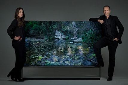Artist duo Alexandrov Klum leaning on a LG SIGNATURE 88 TV