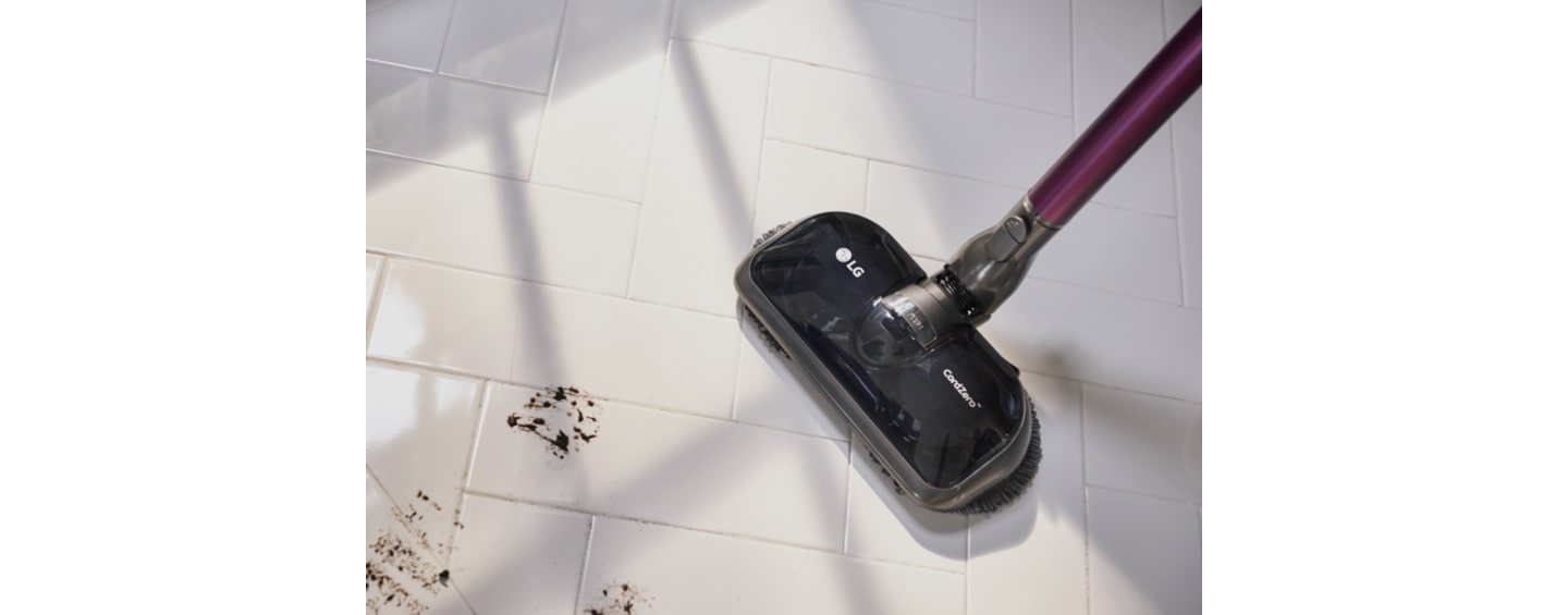 The LG CordZero A9 Kompressor stick vacuum cleaner with Power Mop cleaning the dirty floor messed with footprints