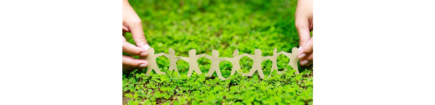 A person holding a paper chain family on a bed of grass.