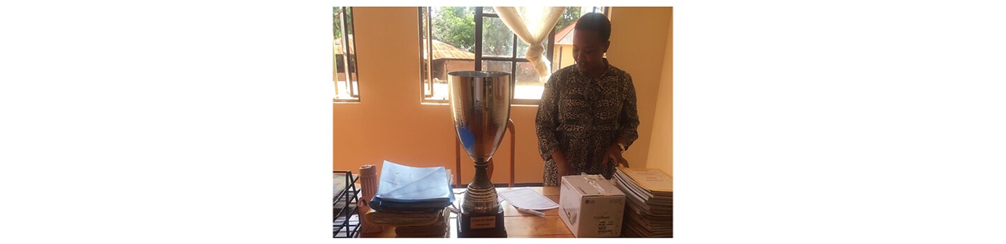 A Tanzanian teacher places the school's new LG CineBeam projector on her desk beside FC Cambounet's trophy.