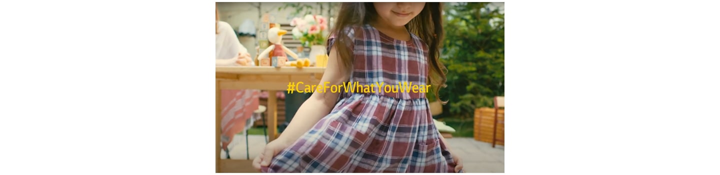 A little girl wearing a cute checkered dress smiling with the Care For What You Wear hashtag overlapping.