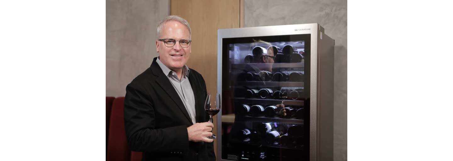 Wine critic and global brand ambassador James Suckling poses next to LG SIGNATURE wine cellar with a glass