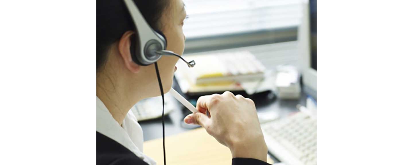 A woman taking a call at her computer while wearing a headset