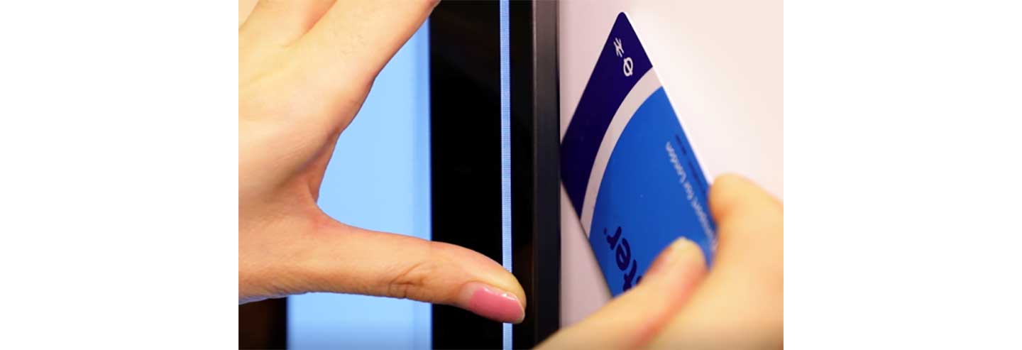 A woman uses her London transportation card to demonstrate just how thin the gap between the wall and the LG GX Gallery TV is