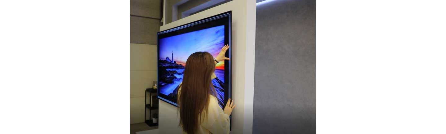 A woman takes a closer look at the thinness of the LG GX Gallery series TV
