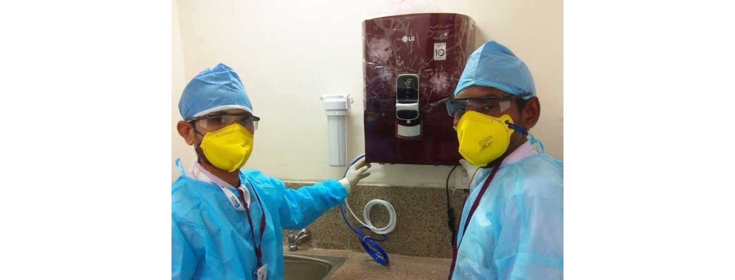 A picture of two medical workers posing in front of the LG PuriCare water purifier that has been donated to medical staff and patients