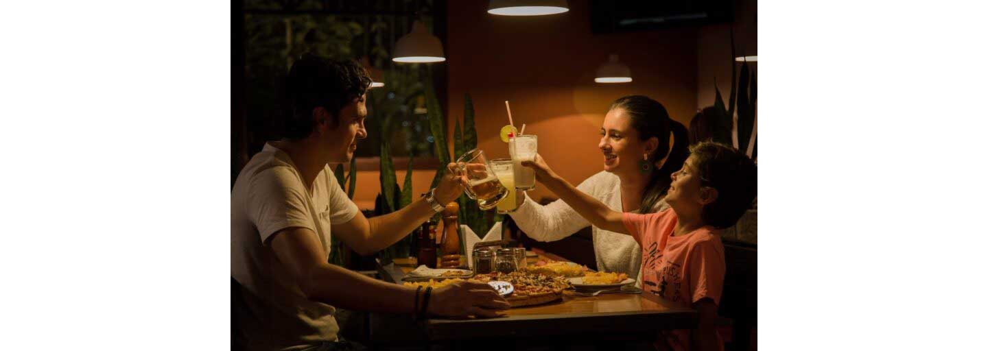 A family ‘cheers’ as they eat around the dinner table under dim lighting