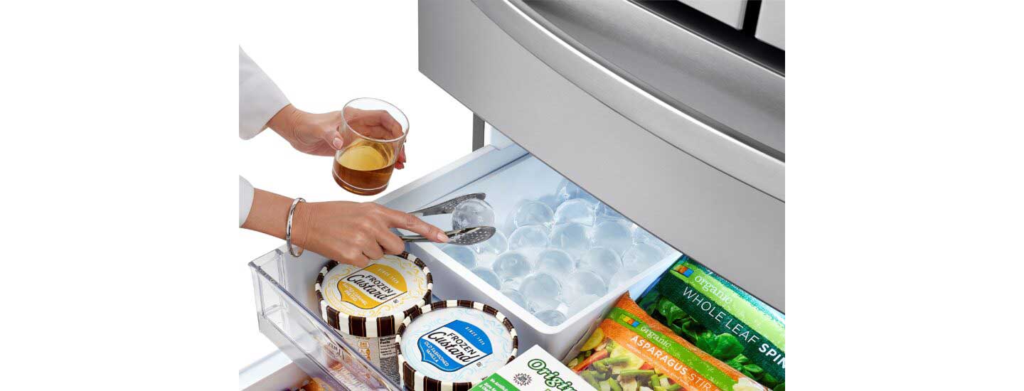 A woman takes an ice ball from the LG refrigerator’s Craft Ice Maker to chill her drink