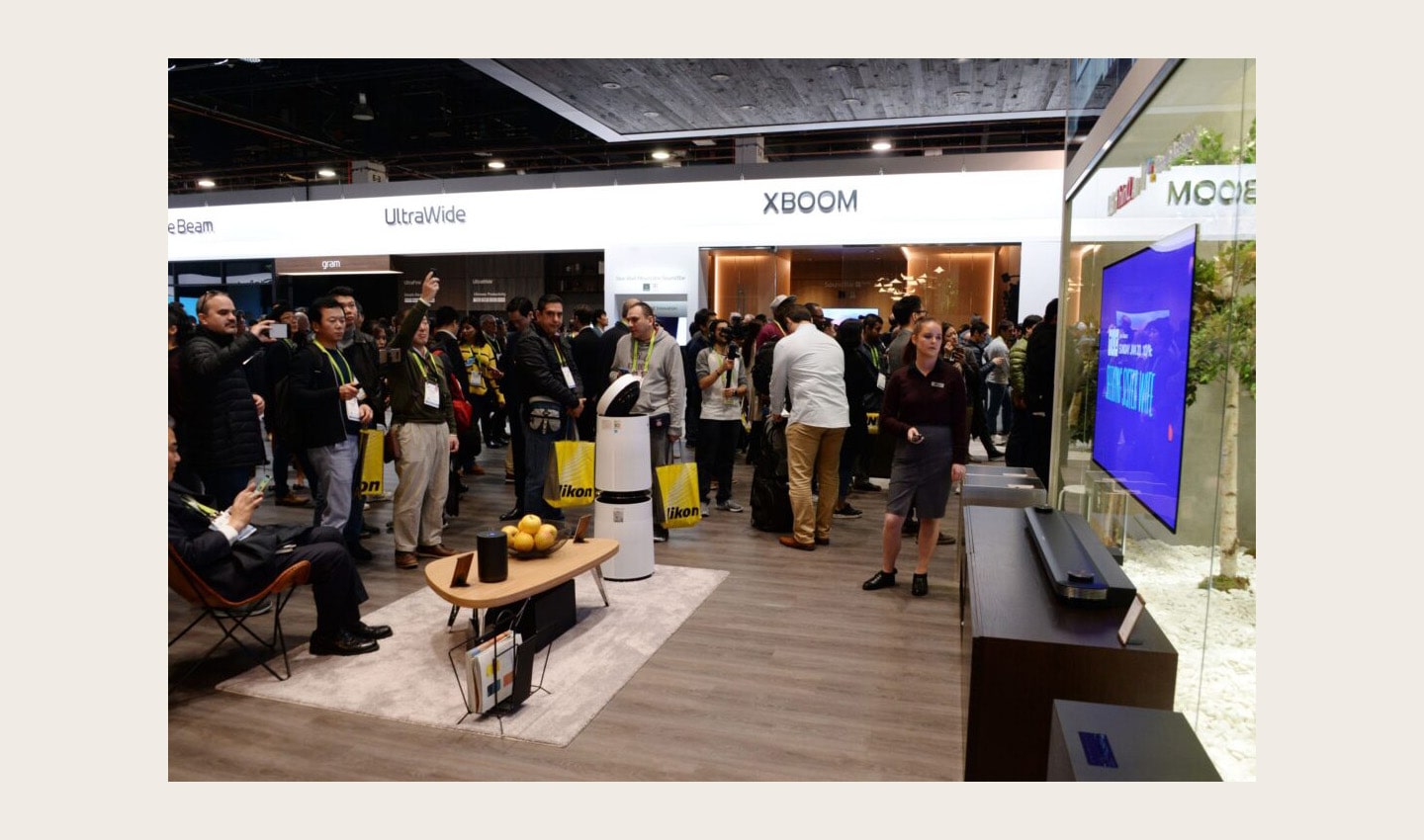 CES attendees walk around the LG HE display zone, looking at an LG SIGNATURE OLED TV W on the wall.