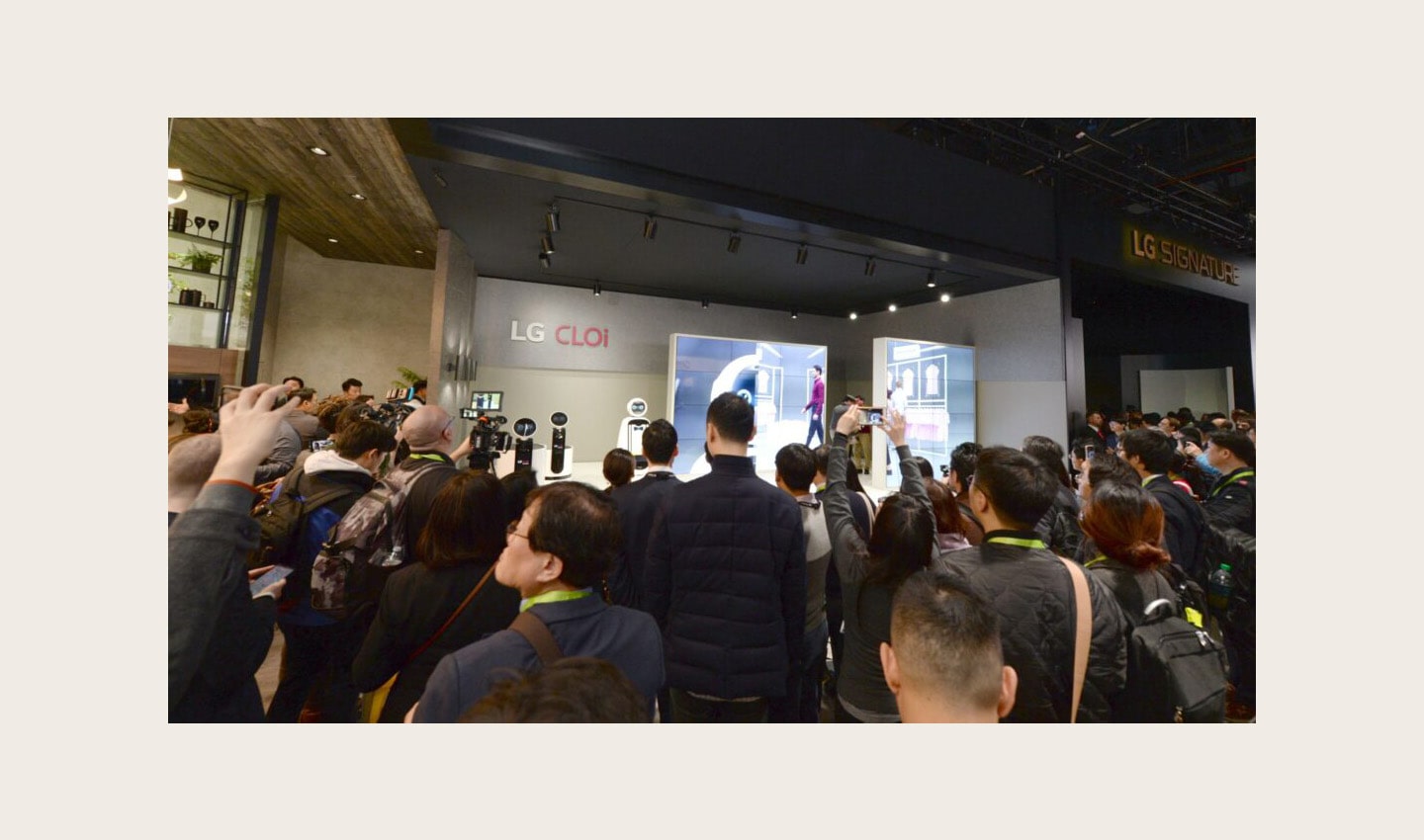 Far shot of a demonstration session for LG's CLOi commercial robots with attendees watching a presentation at the company's CES 2019 booth