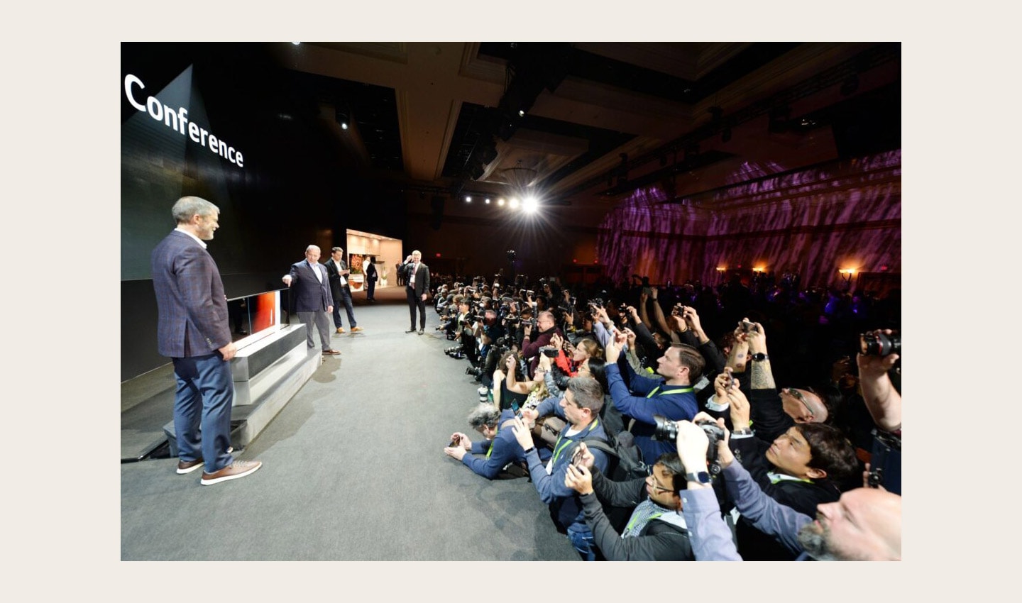 David VanderWall, Senior Vice President of Marketing at LG Electronics USA and Tim Alessi Senior Director of Product Marketing for Home Entertainment Products at LG Electronics USA are onstage discussing the LG SIGNATURE OLED TV R at LG's CES 2019 Press Conference while a number of reporters take pictures of the TV.