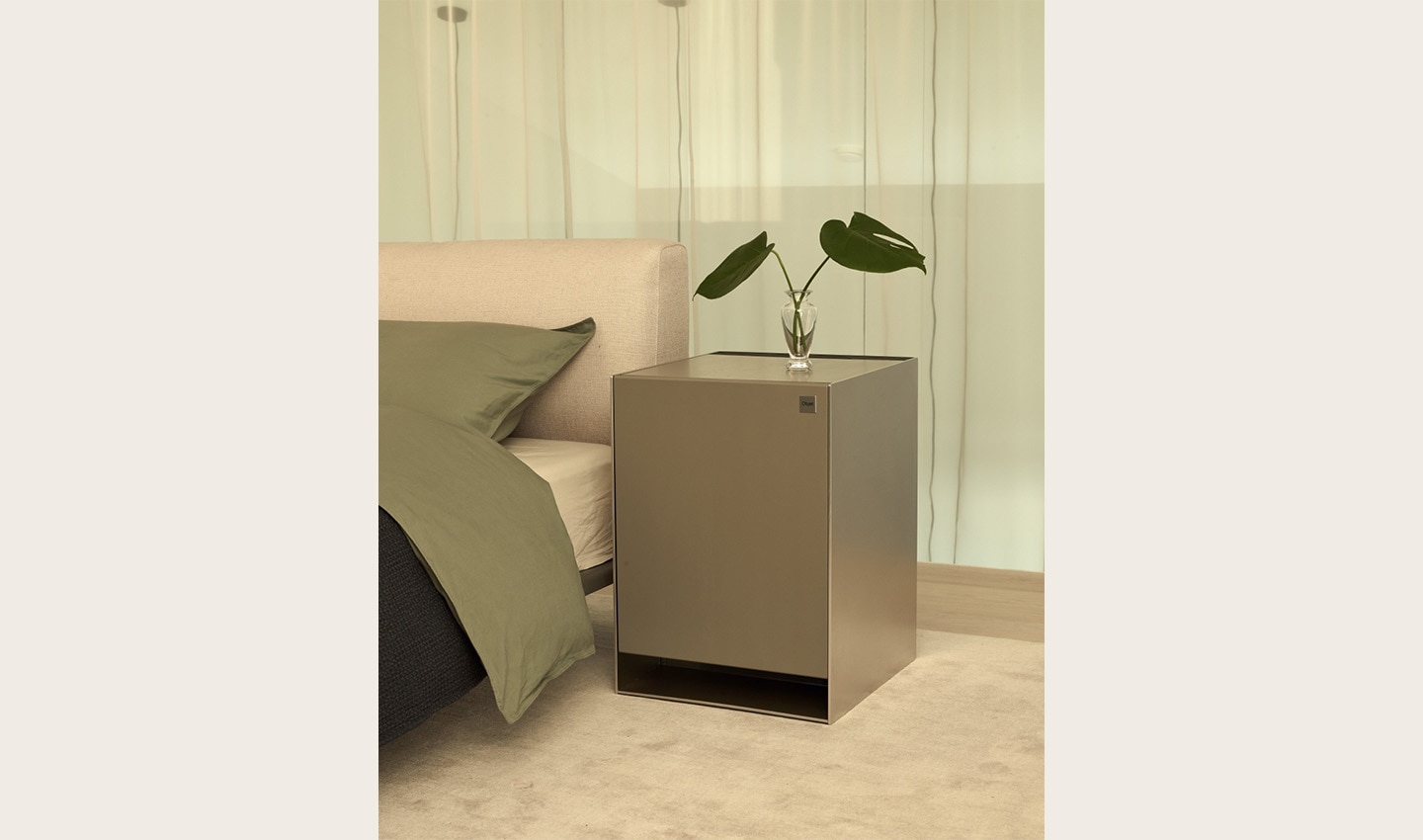 LG OBJET Air Purifier with a plant placed on top of it positioned next to a bed