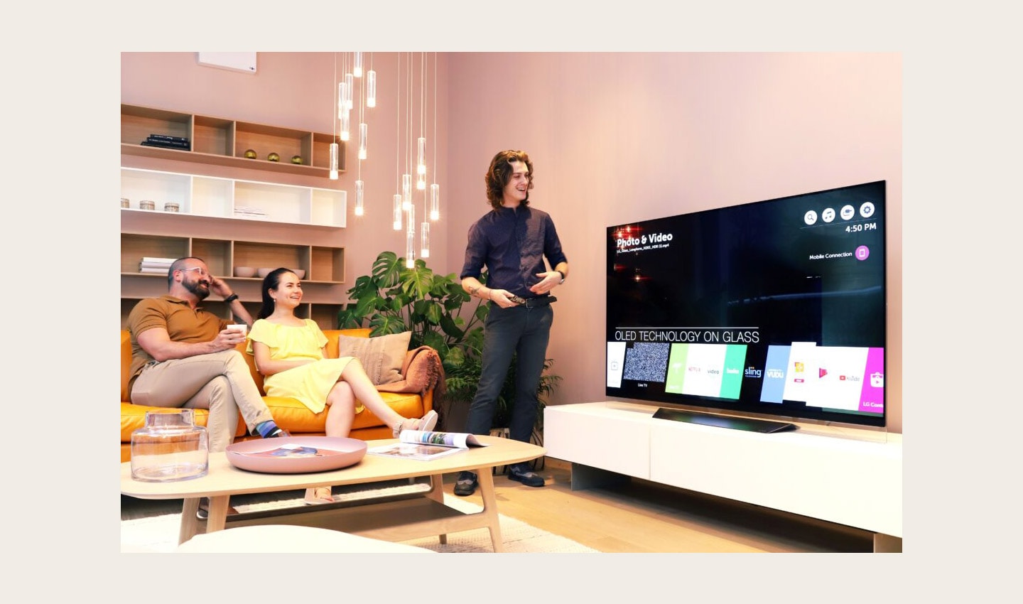 A male attendant tries out the AI assistant features of LG’s ThinQ-eabled OLED TV which displays the application bar of webOS platform on the screen