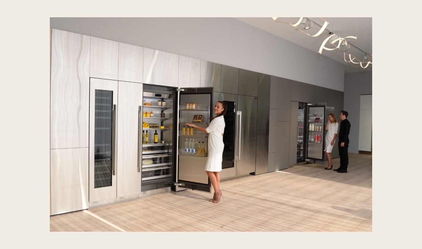 A close view of a refrigerator in the LG Signature Kitchen Suite display zone, a model is opening the fridge door.