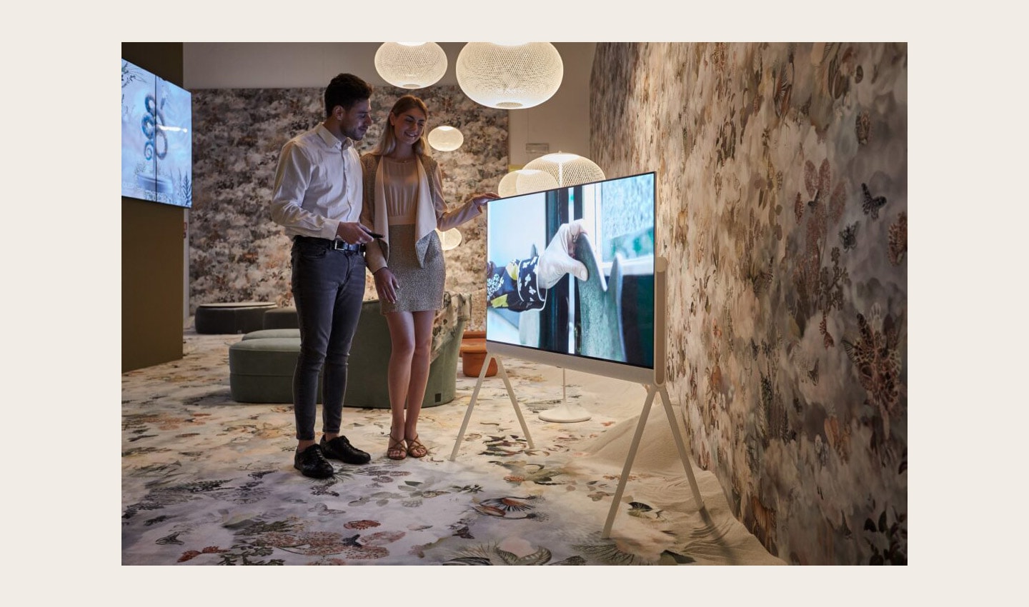 Two visitors taking a closer look at LG OLED Objet Collection, Posé (LX1), displayed at Salone dei Tessuti during Milan Design Week 2022