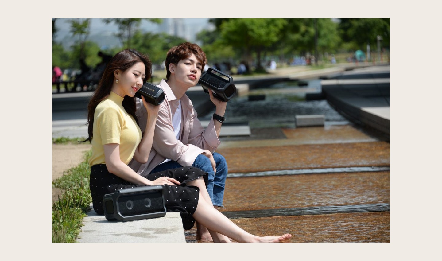 A man and a woman sitting outside enjoying music on their LG XBOOMs