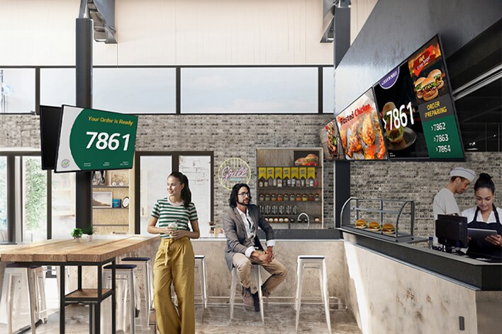 圖像突出顯示快餐店 (QSR) 中的多個顯示屏，上面顯示著排隊號碼和產品圖片等內容。