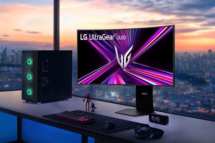 日落時分，俯瞰城市景觀的遊戲桌上擺放著 LG UltraGear OLED 顯示器與電腦。	