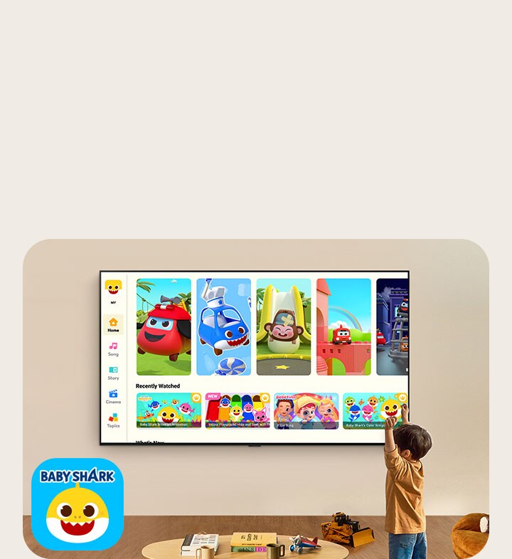 A little boy watches Pinkfong on a wall-mounted LG TV in a living space with kids' toys. 