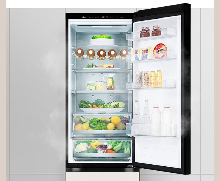 Open LG refrigerator with cake, donuts, fresh produce, dairy, beverages, and condiments neatly organized on shelves and door.