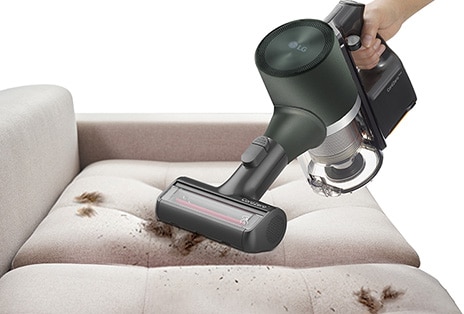 This image shows a Power Drive Mini being used to clean an animal hair and dusty sofa.