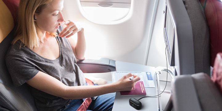 A woman wearing T90S to enjoy in-flight entertainment using the Plug & Wireless function.