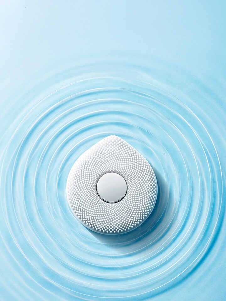 The woman with the WashPop is smiling, and there are drops of water around.