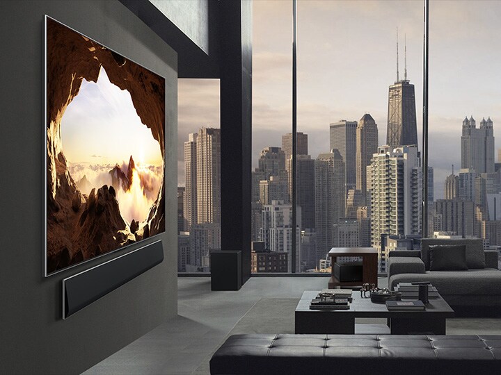 Spacious living room with a view of a cityscape. LG OLED TV is mounted on the wall with an LG Soundbar. From the side, the TV's One Wall Design and ultra slim bezels allow it to blend well with the wall and space. Zero Connect Box is visible, but concealed. 