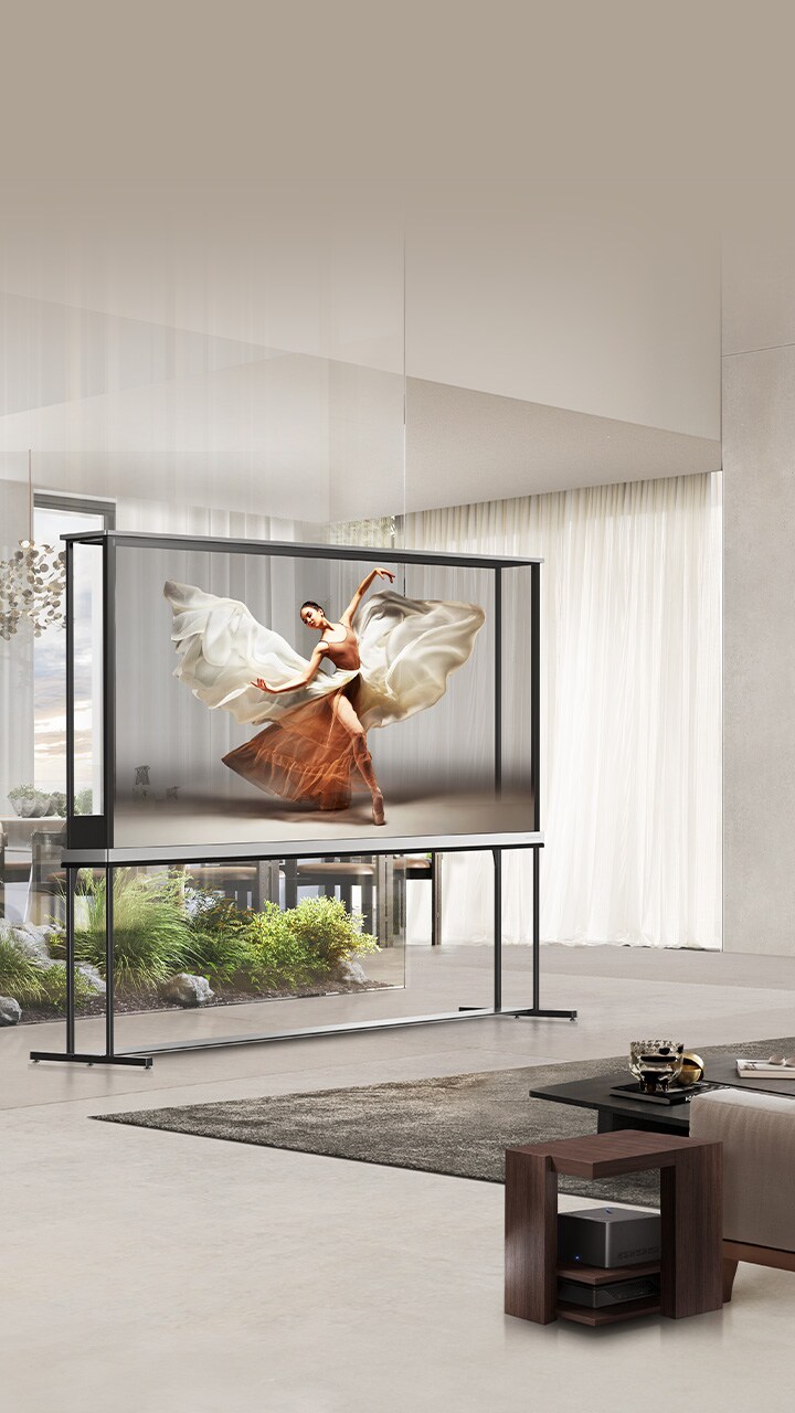 LG Signature OLED T sits in the middle of a modern living room depicting a dancer. Zero Connect Box is placed on a small table next to the couch.
