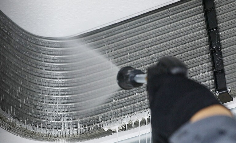 Seorang teknisi sedang membersihkan bagian dalam AC kaset.