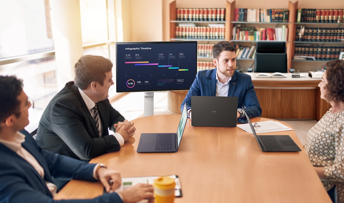 Empat orang duduk mengelilingi meja, mengadakan rapat menggunakan LG Smart Monitor Swing.