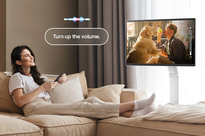 Seorang wanita sedang menaikkan volume LG Smart Monitor Swing menggunakan Magic Remote.