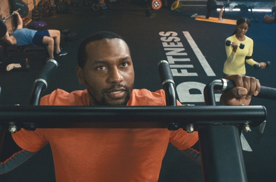 Image shows a man doing pull-ups in a gym.