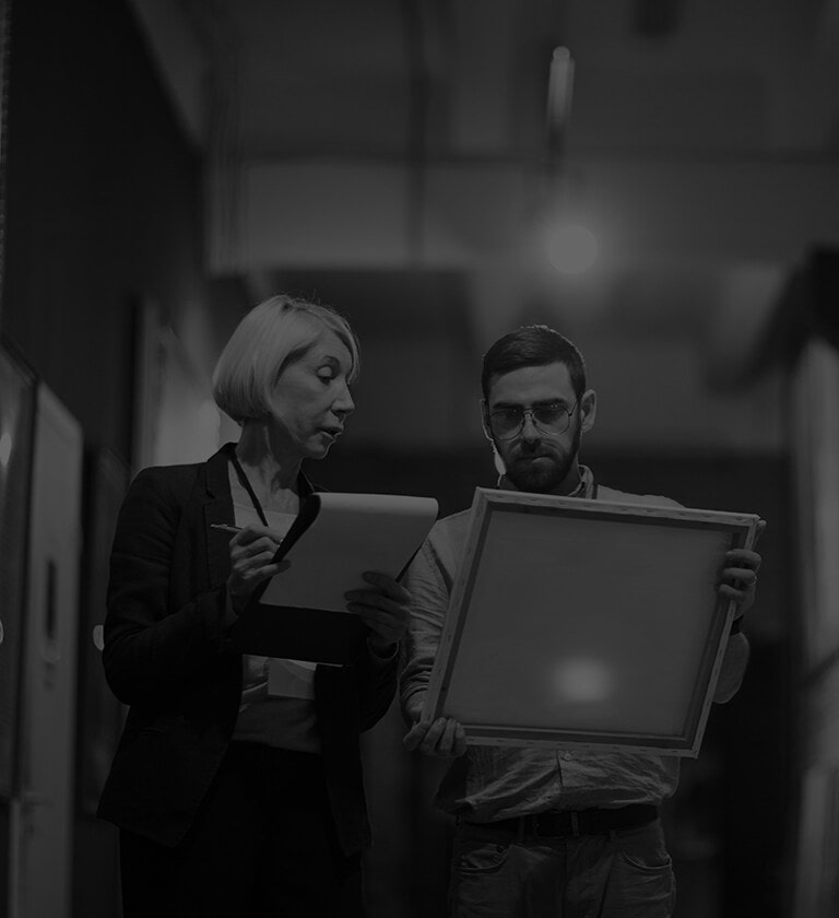 Image of two people looking at a drawing piece in a gallery.