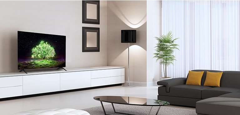 An OLED A1 TV placed in a sensuous living room. On the TV, you can see an image of a brightly glowing green tree.