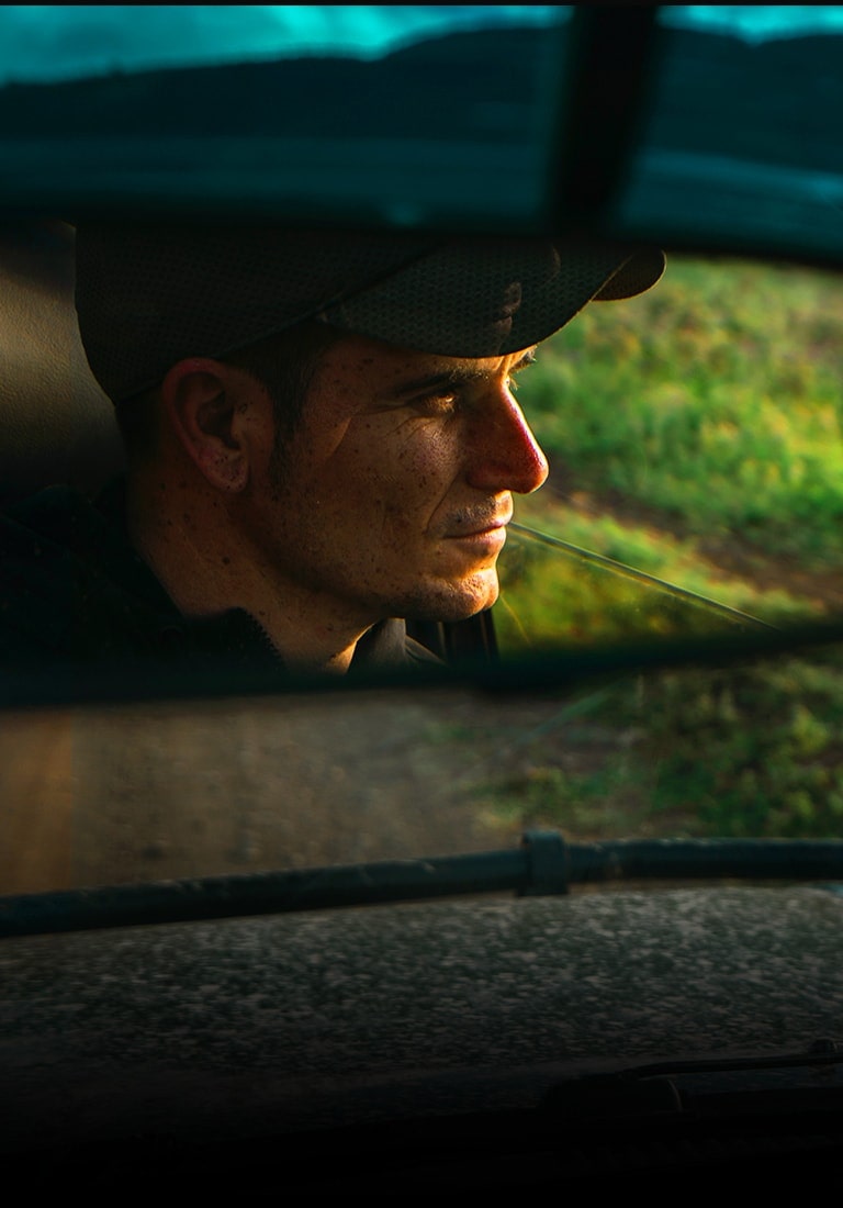 Reflection of man in car rear view mirror. Scene zooms out to show the same scene in QNED TV.