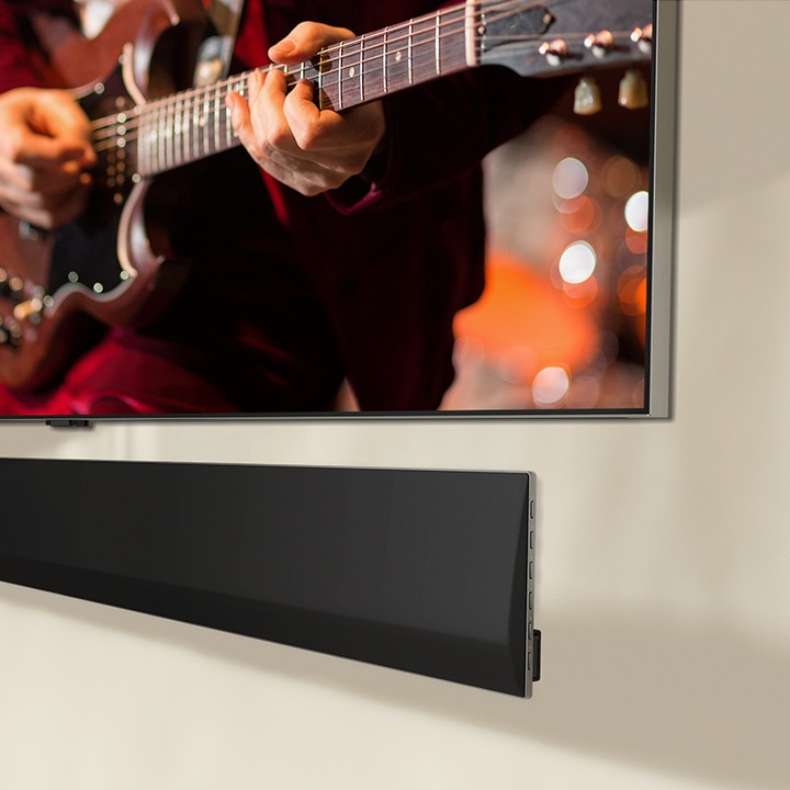 Una prospettiva angolata della parte inferiore della soundbar LG e di un TV LG, appesi al muro.