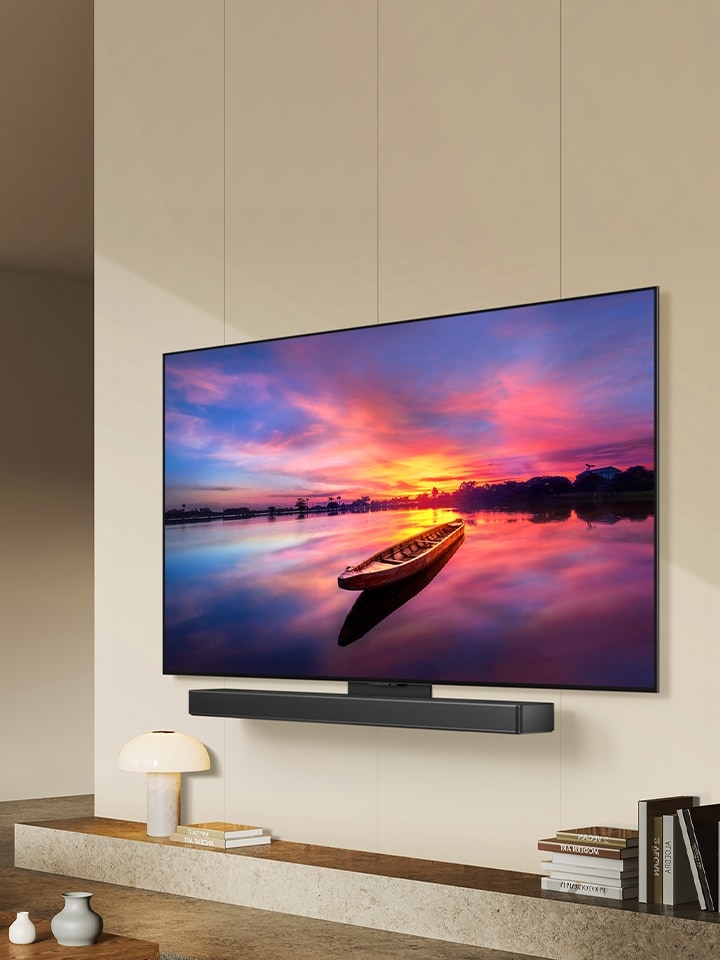 Il TV LG OLED C4 è rivolto a 45 gradi a sinistra e mostra uno splendido tramonto con una barca sul lago. Il TV è collegato a una soundbar LG tramite la staffa Synergy in uno spazio abitativo minimalista.