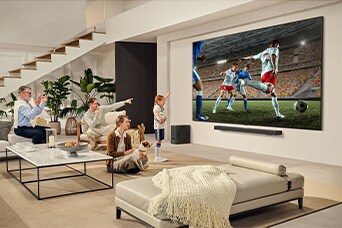 Una famiglia è riunita intorno a una TV ultragrande di LG mentre guardano una partita di calcio emozionante sul grande schermo.