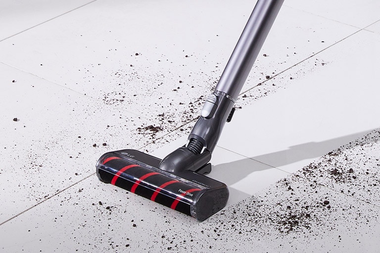 La spazzola Slim per pavimenti duri viene mostrata mentre raccoglie lo sporco nero da un pavimento di superficie dura bianca.