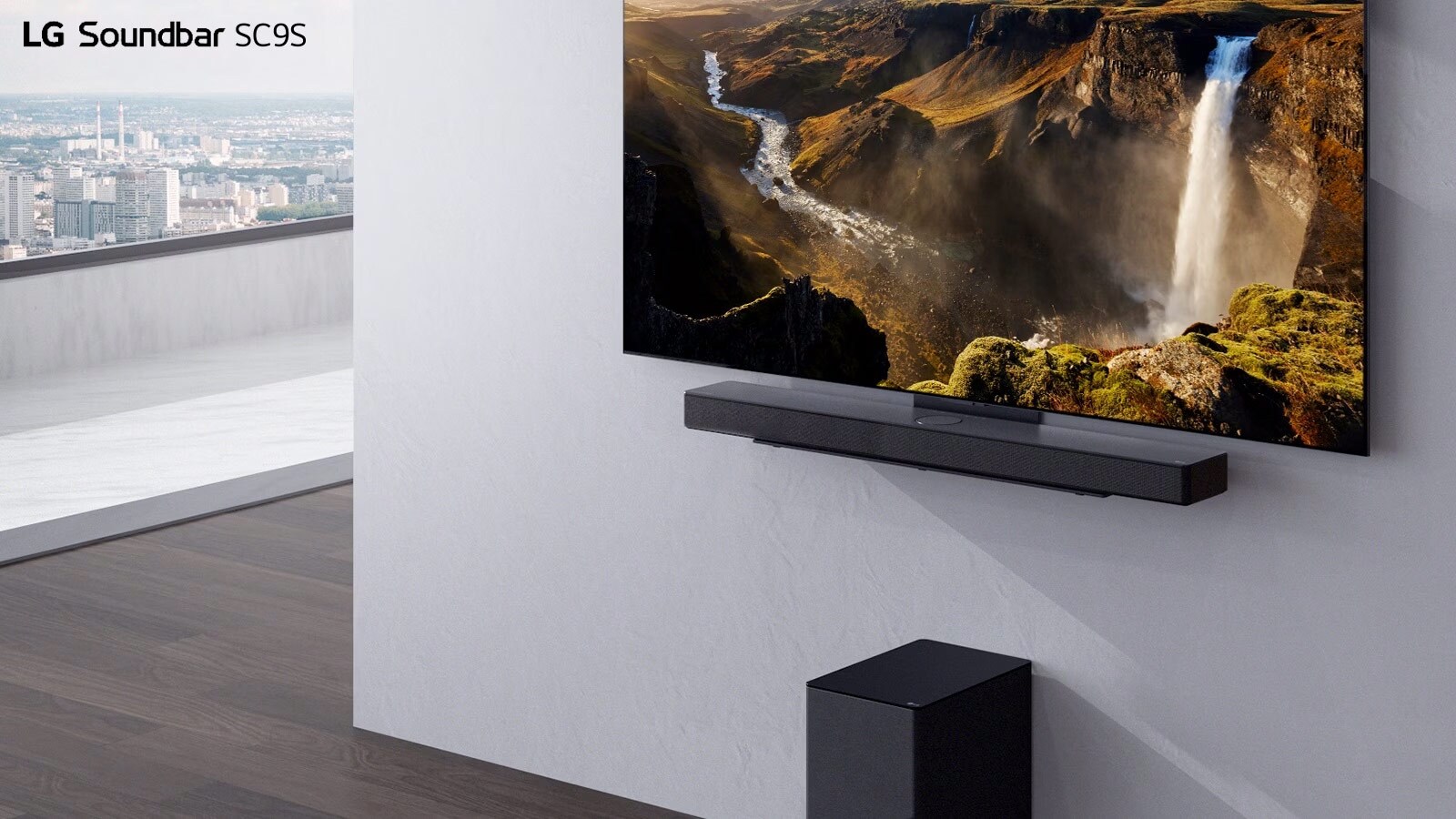 TV e soundbar SC9S LG sospese su una parete bianca. Sotto, un subwoofer nero senza fili è posizionato sul pavimento. Oltre la finestra, sulla sinistra, troviamo una vista della città con il cielo azzurro. 